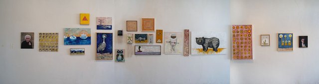 Installation view of a long white gallery wall hung with a single band of paintings and works on paper, including a portrait, a heron, an owl, a rhinoceros, a grid of small circles and several panels of repeated pattern.