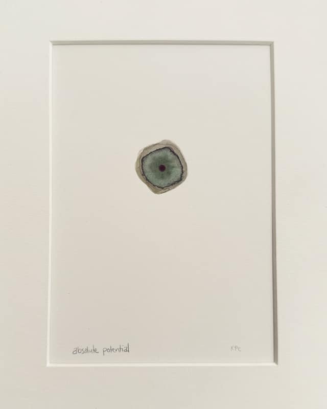 Small gouache and watercolour painting in a white mat: a single rounded, cell-like form in grey-green with a darker ring and a dark centre, alone in the middle of a wide white field. Titled in pencil below, "absolute potential".